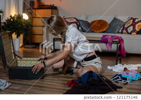 Organizing clothes that are kept inside a vintage suitcase in a cozy and inviting living room 121175146