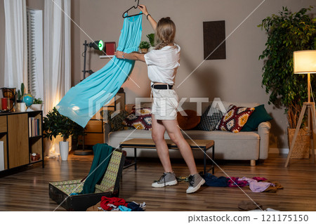 A Fashionable Woman is Skillfully Organizing Her Clothing in a Modern Living Room Space 121175150