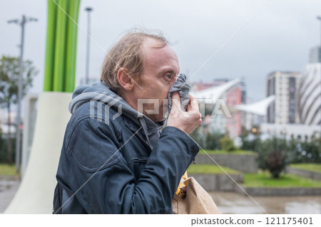 Man blowing his nose in the cold weather Man blowing his nose in the cold weather 121175401