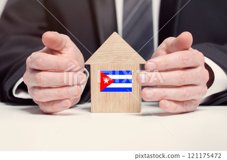Businessman hand holding wooden home model with Cuban flag. insurance and property concepts 121175472