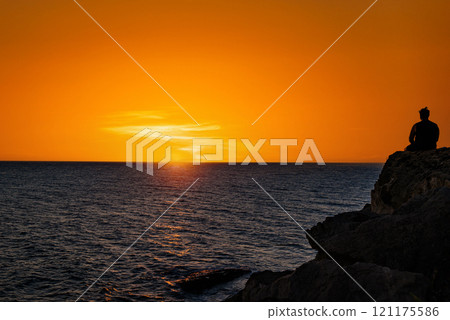 Young man having a beer watching the sunset on the Barbate beach next to the Trafalgar lighthouse, Cadiz Young man having a beer watching the sunset on the Barbate beach next to the Trafalgar lighthouse, Cadiz 121175586