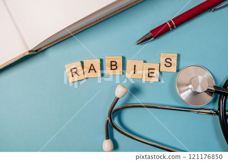 Pen and a stethoscope are on a blue surface with the word rabies 121176850