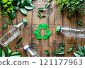 Three plastic bottles with a green recycling symbol on a wooden surface 121177963