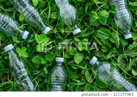 Three plastic bottles with a green recycling symbol on a wooden surface 121177965