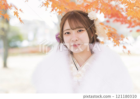 Image of a photo shoot before the coming-of-age ceremony: A woman in a kimono standing among autumn leaves Image of a photo shoot before the coming-of-age ceremony: A woman in a kimono standing among autumn leaves 121180310