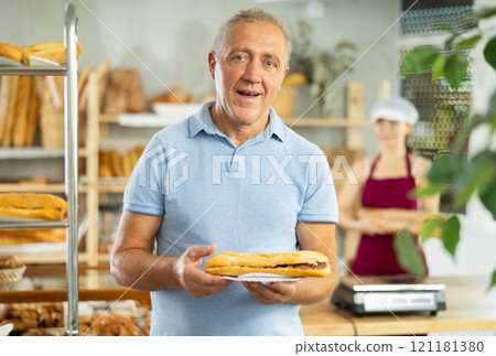 Portrait of male customer holding bocadillo in bakery interior Portrait of male customer holding bocadillo in bakery interior 121181380