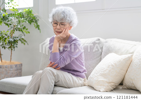 Senior woman sitting on sofa 121181444