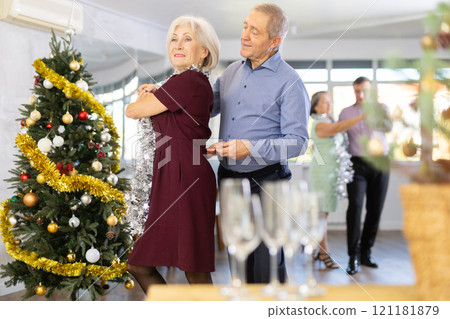 Smiling elderly woman and partner successfully perform mesmerizing movements of paso doble dance during celebration Christmas and New Year Smiling elderly woman and partner successfully perform mesmerizing movements of paso doble dance during celebration Christmas and New Year 121181879