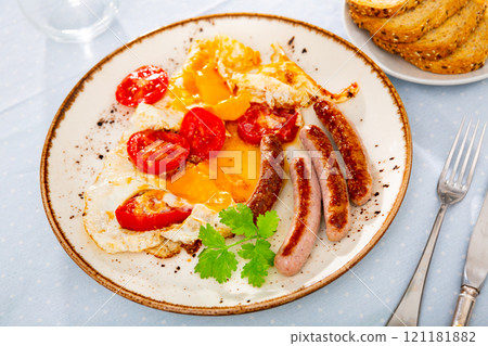 Homemade hearty breakfast - fried eggs with frankfurter and tomato 121181882