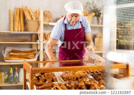 Elderly man seller puts croissants in bag Elderly man seller puts croissants in bag 121181897