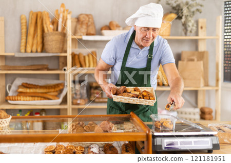 Elderly male seller puts pastry croissant in plastic package, put on scales, sets price of product Elderly male seller puts pastry croissant in plastic package, put on scales, sets price of product 121181951