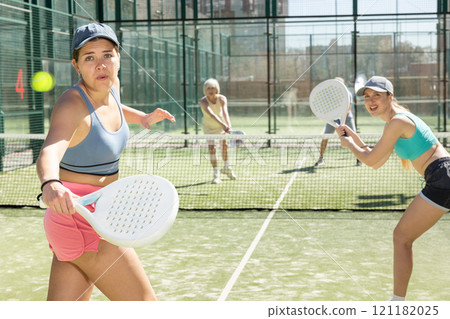 Young woman looking back after the ball while playing Padel Tennis in tennis court Young woman looking back after the ball while playing Padel Tennis in tennis court 121182025