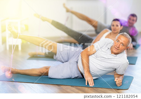 Elderly man exercising with pilates loop 121182054