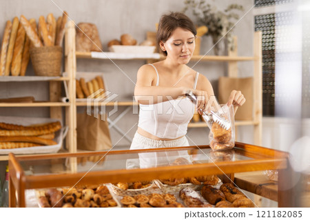 European young woman visitor puts croissant in plastic disposable bag 121182085