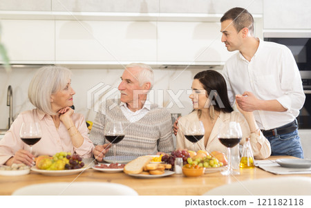Senior parents and young couple sitting at table drinking wine and having conversation 121182118