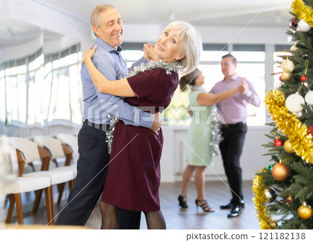 In studio decorated for New Year, elderly man and woman perky dance pair discofox. 121182138