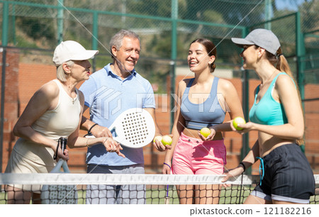 Senior couple and their daughters discussing padel game in court 121182216