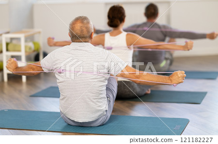Group of elderly women and men doing stretching exercises with resistance band. Good mood and healthy lifestyle concept 121182227