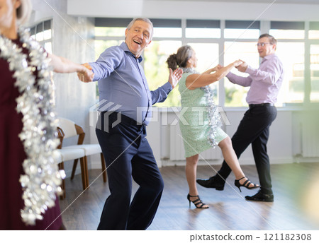 Active mature man and woman enjoying celebration Christmas at ballroom and dancing rock and roll dance Active mature man and woman enjoying celebration Christmas at ballroom and dancing rock and roll dance 121182308