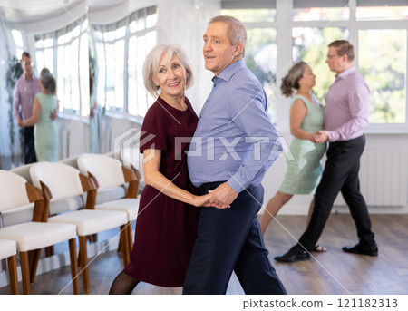 Pairs of mature amateur dancers enthusiastically performs romantic tango dance in dance salon 121182313
