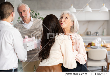 Happy senior man and woman welcoming young couple at home 121182316