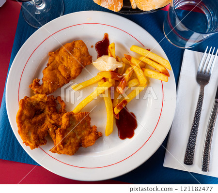 Crisp chicken nuggets with golden brown crust and french fries 121182477