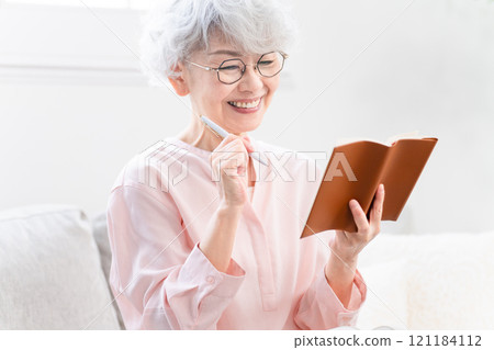Senior woman looking at her schedule book 121184112