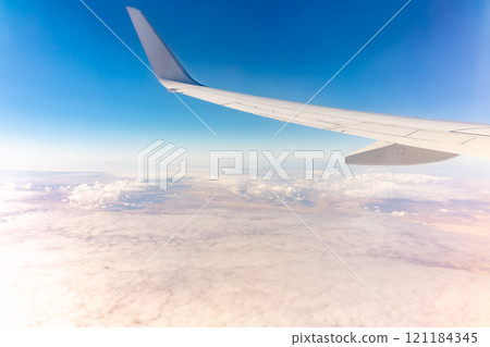 View from the airplane window at a beautiful cloudy sky and the airplane wing 121184345