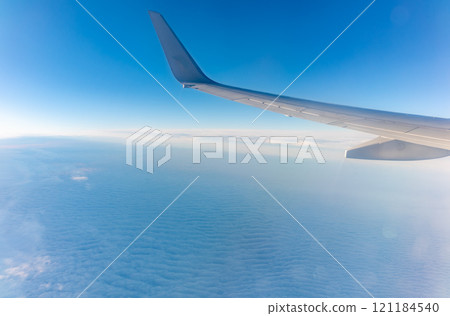 View from the airplane window at a beautiful cloudy sky and the airplane wing 121184540