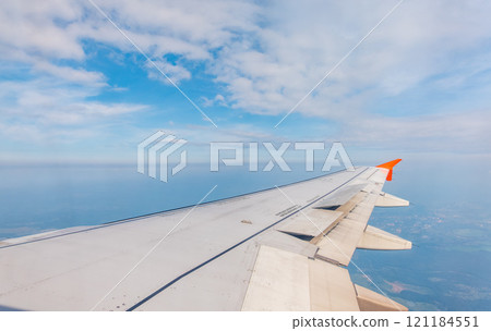 View from the airplane window at a beautiful cloudy sky and the airplane wing 121184551
