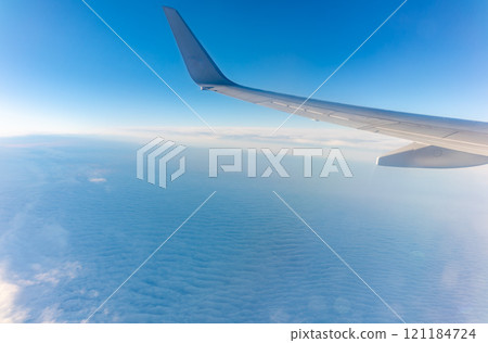 View from the airplane window at a beautiful cloudy sky and the airplane wing 121184724
