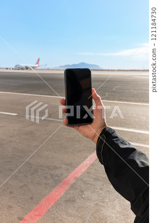 Girl holds a smartphone with a black screen close-up. Phone on the background of the airport with an airplane 121184730
