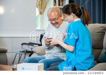 Asian doctor with physician visit senior male patient consult medicine dosage at house in living room, Woman nurse caregiver showing prescription drug to senior man at nursing home, healthcare support 121184852