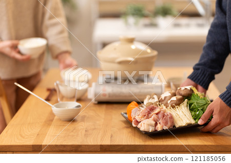 A middle-aged couple preparing hotpot dinner in the living room on a winter night 121185056