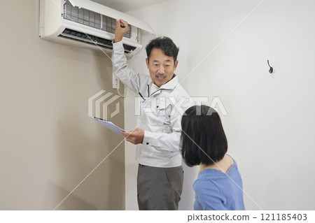 A contractor's worker checking an air conditioner for malfunctions 121185403