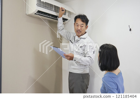 A contractor's worker checking an air conditioner for malfunctions 121185404