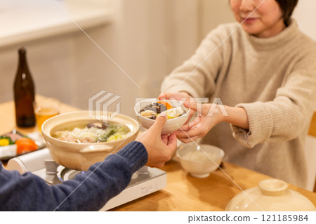 冬夜,一對中年夫妻在客廳享用火鍋晚餐 冬夜,一對中年夫妻在客廳享用火鍋晚餐 121185984