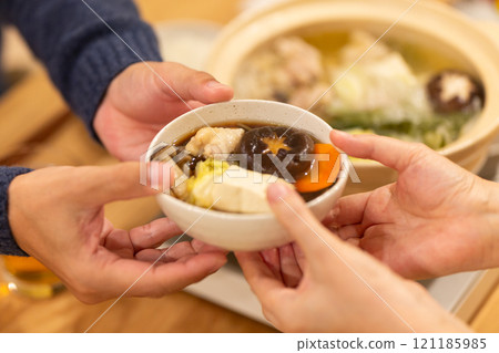 冬夜,一對中年夫妻在客廳享用火鍋晚餐 冬夜,一對中年夫妻在客廳享用火鍋晚餐 121185985