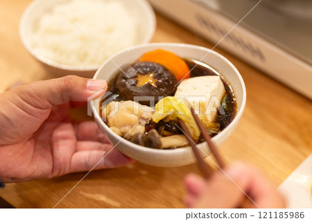 Hands of a man enjoying hot pot dinner in the living room on a winter night 121185986