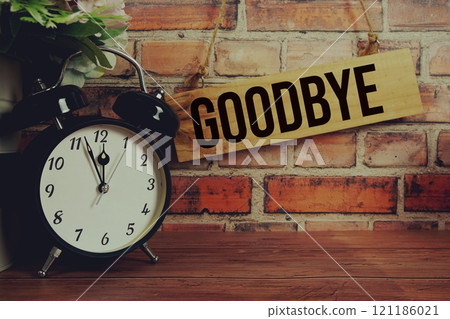 Time to say Goodbye text on wooden sign with alarm clcok on wooden background 121186021