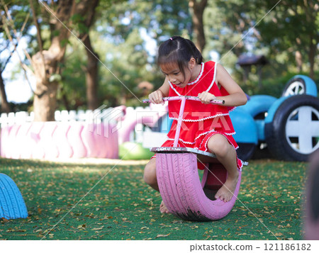 Cute girl playing in the playground during summer vacation. Happy children having fun in an outdoor park. Cute girl playing in the playground during summer vacation. Happy children having fun in an outdoor park. 121186182