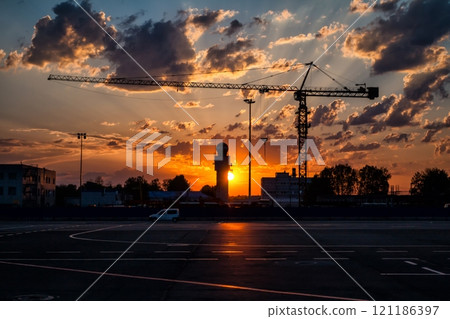 Tower crane on the background of a picturesque sunrise in an empty airport Tower crane on the background of a picturesque sunrise in an empty airport 121186397