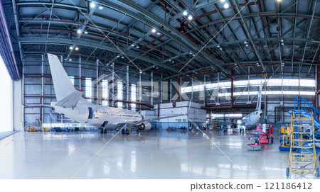 Passenger aircrafts under maintenance. Checking mechanical systems for flight operations. Panorama of airplanes in the hangar Passenger aircrafts under maintenance. Checking mechanical systems for flight operations. Panorama of airplanes in the hangar 121186412