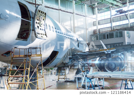 Passenger jet plane under maintenance in the hangar. Checking mechanical systems for flight operations. Close-up view the back of the aircraft with the door open Passenger jet plane under maintenance in the hangar. Checking mechanical systems for flight operations. Close-up view the back of the aircraft with the door open 121186414