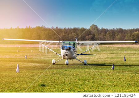 Taxiing a small private airplane on the airfield in the rays of the evening sun 121186424
