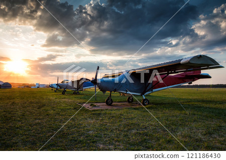 Small private airplanes parked at the airfield at picturesque sunset 121186430