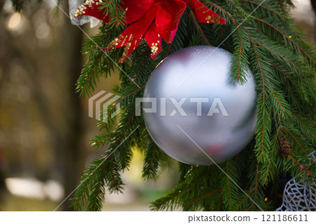 Silver Ornament Hanging on a Festive Christmas Tree with Bright Decorations 121186611