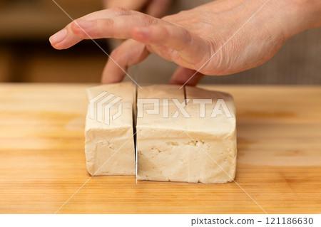 一位中年婦女的手在切板上切硬豆腐 一位中年婦女的手在切板上切硬豆腐 121186630