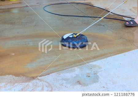 Water sprays onto concrete surface as pressure washer is used for cleaning, showing effective outdoor maintenance. Water sprays onto concrete surface as pressure washer is used for cleaning, showing effective outdoor maintenance. 121188776