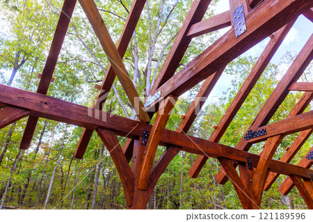 Wooden framework gazebo rises among green trees under clear blue sky, during construction built gazebo 121189596